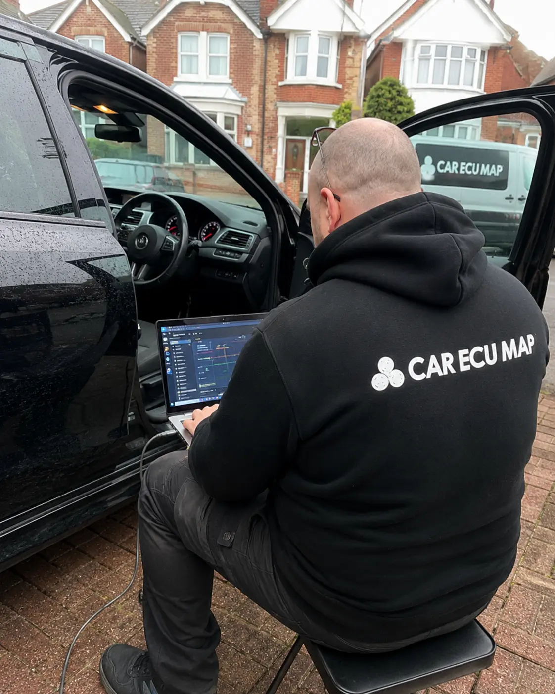 CarEcuMapDoctor technician performing mobile ECU remapping on a black SUV at a customer's home in Kent