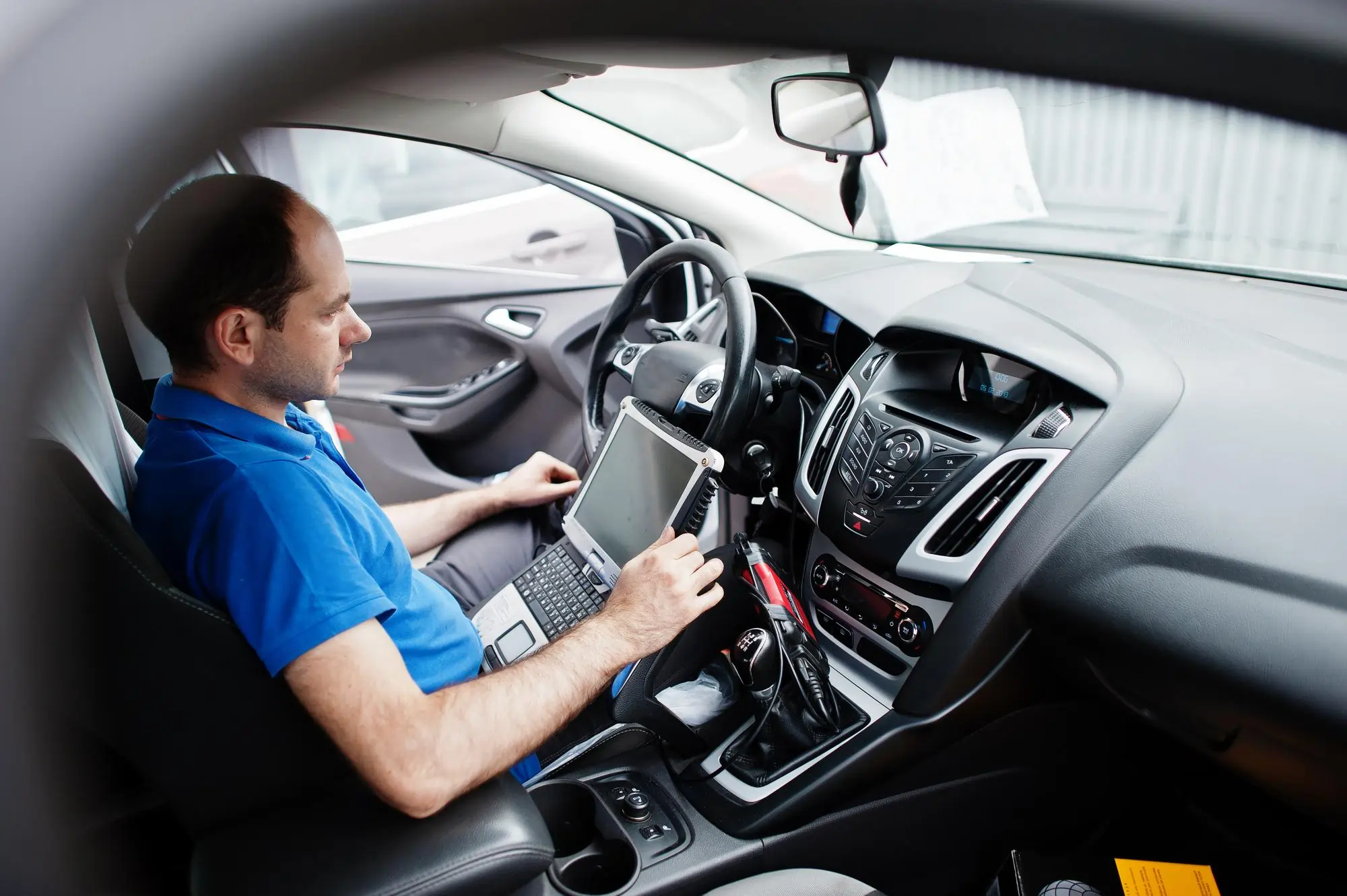 Mobile ECU remapping technician using diagnostic laptop inside a car in Kent